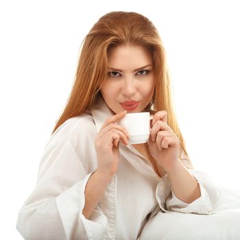 Portrait of a sexy red-haired girl drinking coffee in bed isolated on white background