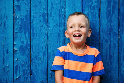 Portrait of happy joyful beautiful little boy against the old textured blue wall
