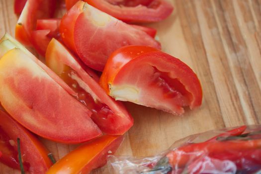 Tomatoes and peppers for cooking on a wood block.