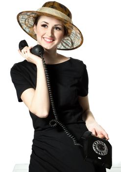 Portrait of a beautiful brown-eyed woman in a little black dress with a vintage telephone isolated on white background