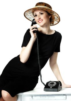 Portrait of a beautiful brown-eyed woman in a little black dress with a vintage telephone isolated on white background