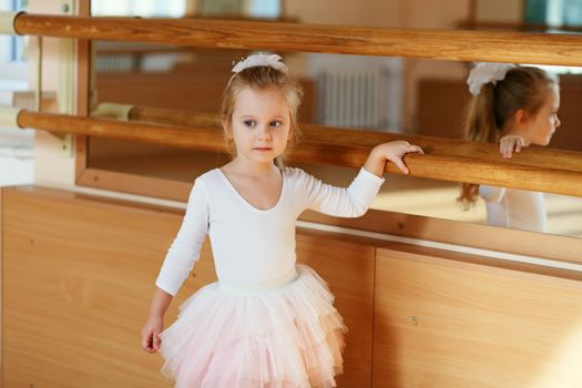Ballerina little girl standing near mirror in the gym