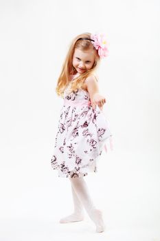Full length portrait of a cute little blonde girl dancing against white background