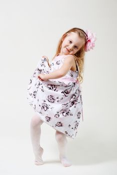 Full length portrait of a cute little blonde girl dancing against white background