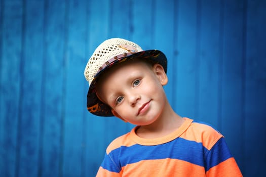 Portrait of happy joyful beautiful little boy against the old textured blue wall