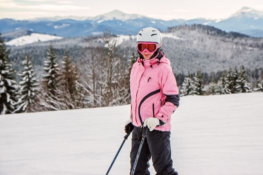 Portrait of a young woman in a ski outfit and helmet in the snowy mountains