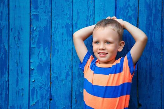 Portrait of happy joyful beautiful little boy against the old textured blue wall