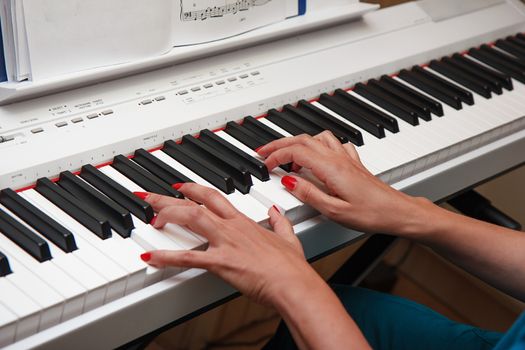 Hands of a young woman playing the electronic piano