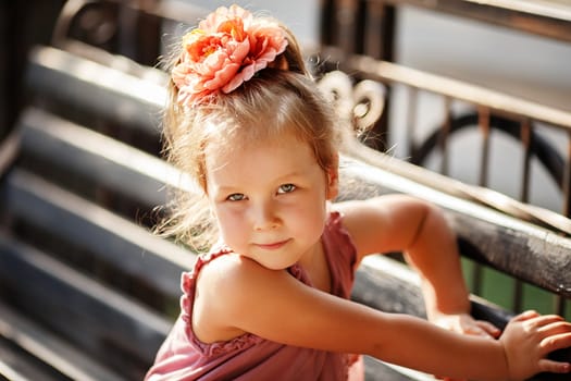 Portrait of a smiling pretty little girl sitting on a park bench