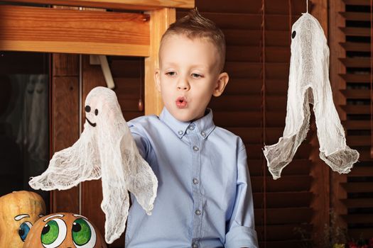 Halloween party with child holding toy ghost. Cute Little Boy having fun in Halloween decorations