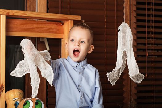 Cute Little Boy having fun in Halloween decorations. Halloween party with child holding toy ghost