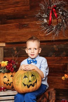 Halloween party with child holding painted pumpkin. Cute Little Boy having fun in Halloween decorations