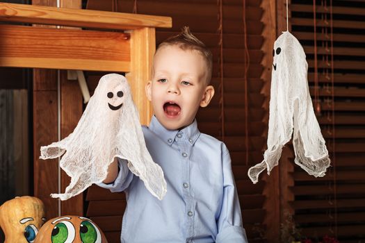 Cute Little Boy having fun in Halloween decorations. Halloween party with child holding toy ghost