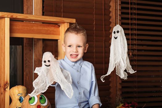 Cute Little Boy having fun in Halloween decorations. Halloween party with child holding toy ghost