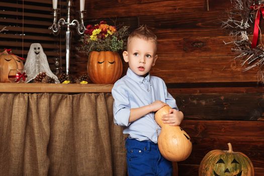 Cute Little Boy having fun in Halloween decorations. Halloween party with child holding painted pumpkin. Your text