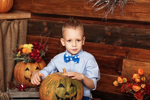 Halloween party with child holding painted pumpkin. Cute Little Boy having fun in Halloween decorations