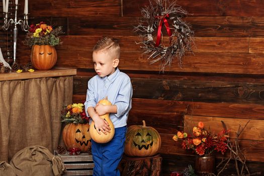 Cute Little Boy having fun in Halloween decorations. Halloween party with child holding painted pumpkin