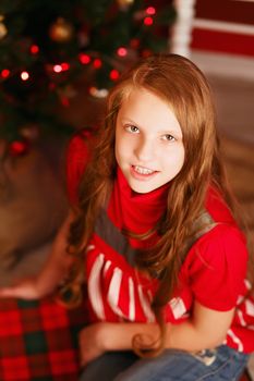 Portrait of a pretty smiling teen girl with long hair in interior with Christmas decorations