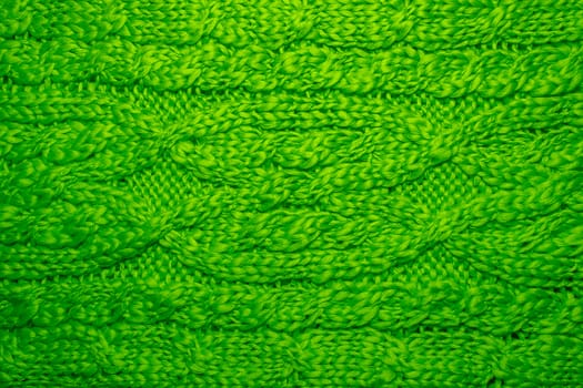 Wool sweater or scarf texture close up. Knitted jersey background with a relief pattern. Braids in machine knitting pattern. Wool hand-knitted or machine knitting pattern. Closeup Fabric Background