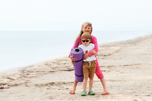 Two small children on the beach in cloudy weather.