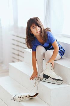 Little girl trying on a large ice skating. Little kid and skates