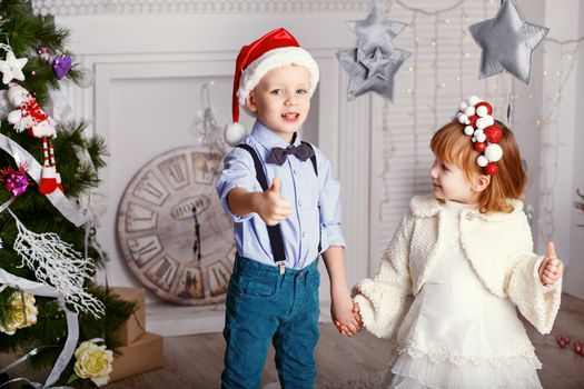 Two little children having fun near the Christmas tree. New year celebration. Happy kids and family.