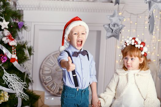 Two little children having fun near the Christmas tree. New year celebration. Happy kids and family.