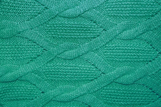 Green wool sweater texture close up. Knitted jersey background with a relief pattern