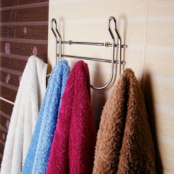 Clean Colored towels hanging on the rack in the bathroom. Focus on the top of the hook and towels