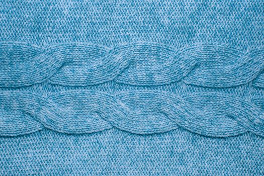Wool sweater texture close up. Knitted jersey background with a relief pattern. Braids in machine knitting pattern