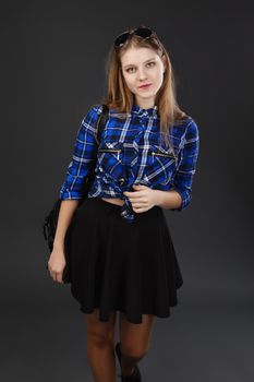 Portrait of a girl in a plaid shirt and black skirt, with a black leather backpack on her shoulder. Portrait of a girl shot on a wide-angle lens