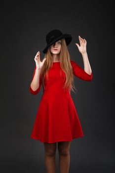 A beautiful girl in red dress and black felt hat.