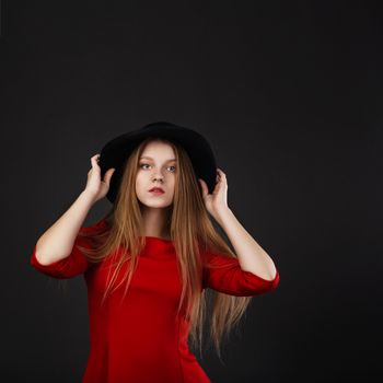 Portrait of beautiful young girl in red dress and black felt hat.