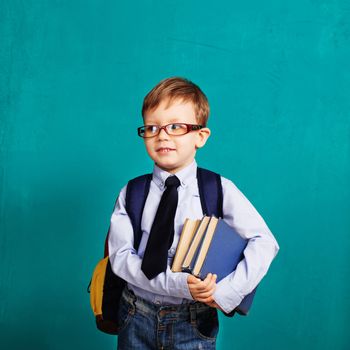 Book, school, kid. Diligent, sedulous, studious student holding books. Cheerful smiling little kid with big backpack against chalkboard. Looking at camera. School concept. Back to School