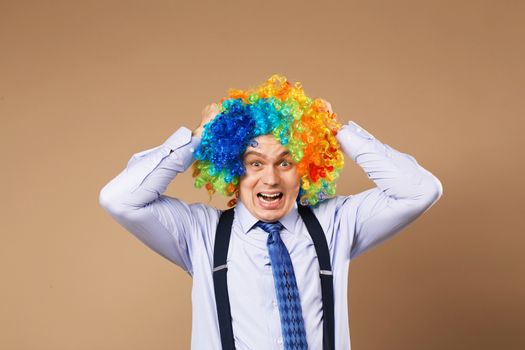 screaming businessman with large colorful wig. Close-up Portrait of business man in clown wig. Business concept