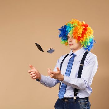 Businessman juggling mobile phones. Close-up Portrait of business man in clown wig. Business concept