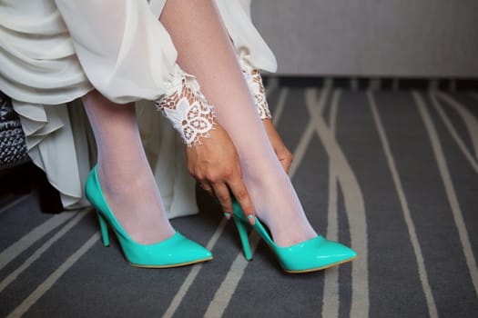 Bride dresses shoes before the wedding ceremony. Bride attributes. Morning of the bride. Preparations for the wedding ceremony