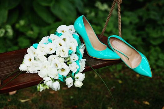 Attributes runaway bride. Wedding bouquet of white roses and blue ribbons and blue patent leather high-heeled shoes