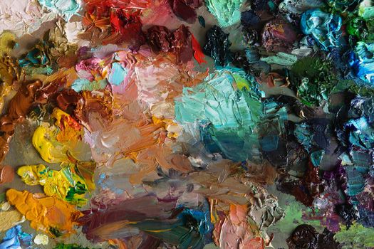 artists oil paints on wooden palette. macro artist's palette, texture mixed oil paints in different colors and saturation. art palette background