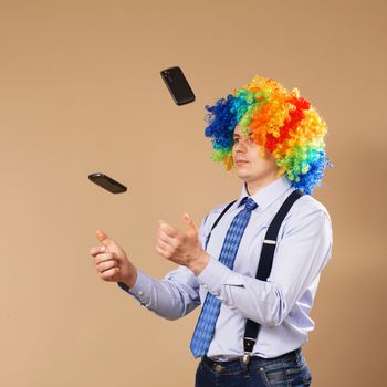 Businessman juggling mobile phones. Close-up Portrait of business man in clown wig. Business concept