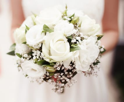 Bride holding bouquet of white roses outside