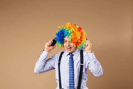 Businessman respond to numerous phone calls. Close-up Portrait of business man in clown wig. Business concept