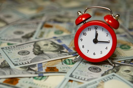 Time - money. Business concept. Analog hours on a heap of paper dollars. Clock and money