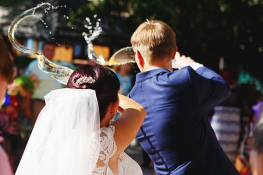 wedding traditions. Bride and groom pouring out champagne over the left shoulder