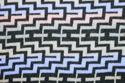 a geometric pattern on a knitted fabric. Christmas ornamental knitting. knitted sweater background texture. Real knitted fabric textured background