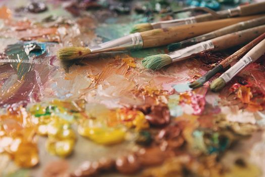 artists brushes and oil paints on wooden palette. Artist paintbrushes over palette with oil colors. palette with paintbrush and palette-knife