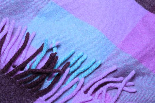 Soft and warm folded alpaca wool blanket with fringe. blue and violet wool plaid texture macro shot. Wool plaid texture with fringe. Wool blanket