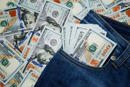 Macro shot of trendy jeans with american 100 dollars bills on its pocket. 100 dollar bill sticking out from a blue jean pocket