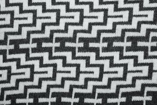 a geometric pattern on a knitted fabric. Christmas ornamental knitting. knitted sweater background texture. Real knitted fabric textured background