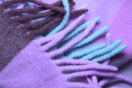 Soft and warm folded alpaca wool blanket with fringe. Violet wool plaid texture macro shot. Wool plaid texture with fringe. Wool blanket